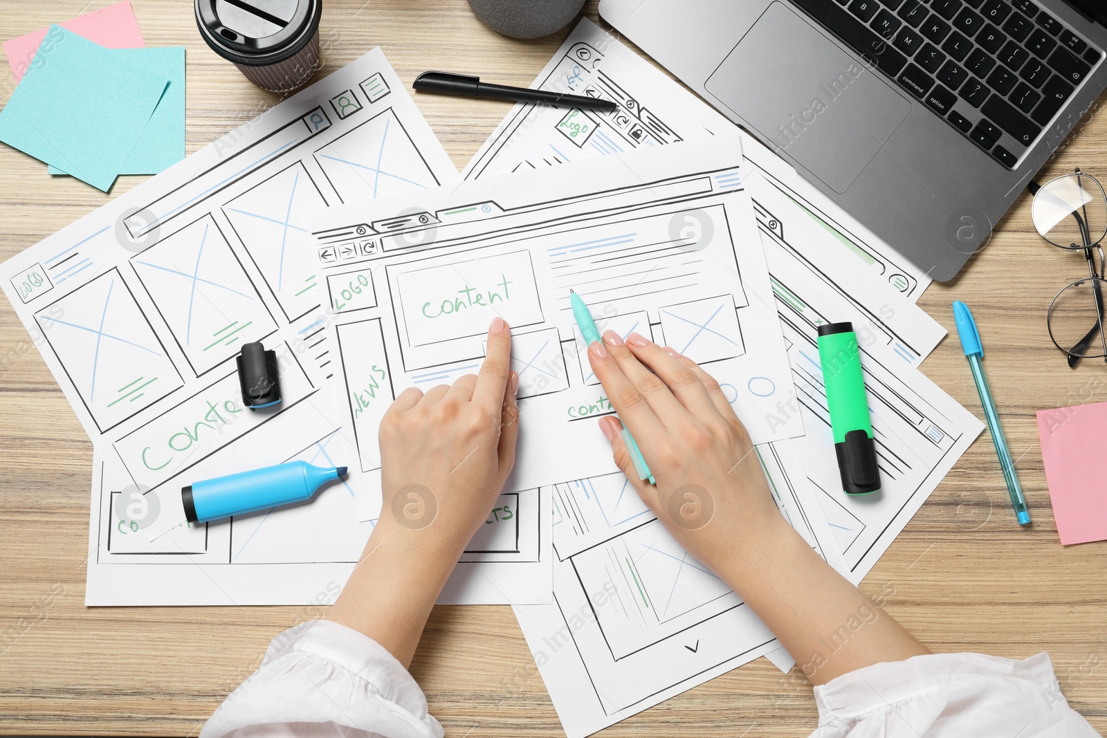 Photo of Website designer creating wireframe on paper with pen at wooden table, top view