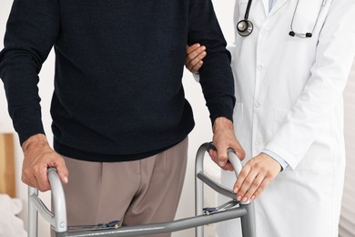 Photo of Doctor helping senior man with walking frame in clinic, closeup