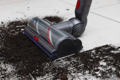 Photo of Cleaning floor with cordless vacuum cleaner indoors, closeup