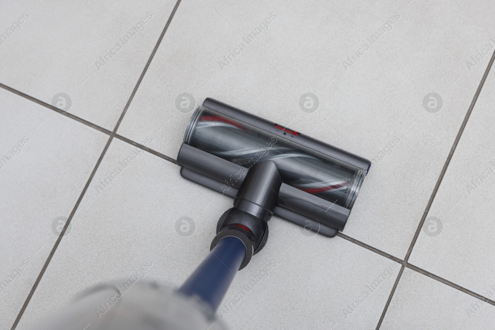 Photo of Cleaning floor with cordless vacuum cleaner indoors, top view