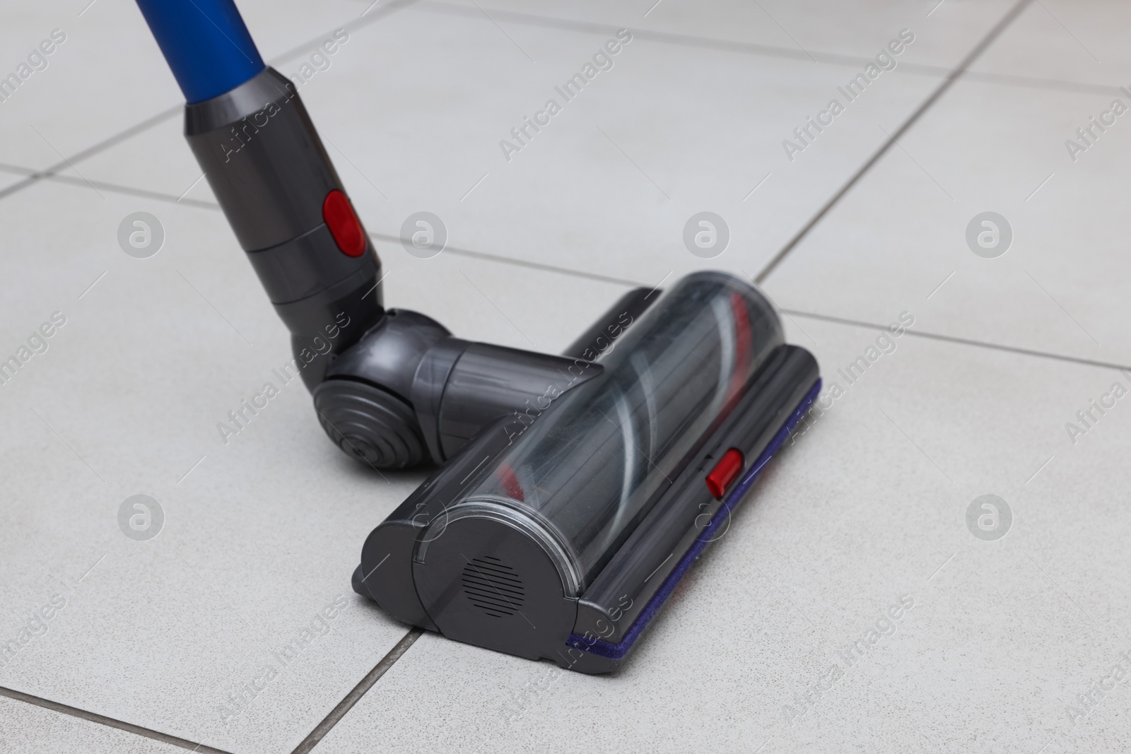 Photo of Cleaning floor with cordless vacuum cleaner indoors, closeup