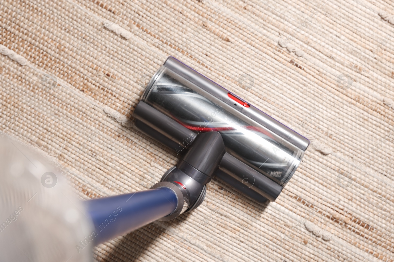 Photo of Cleaning carpet with cordless vacuum cleaner indoors, top view