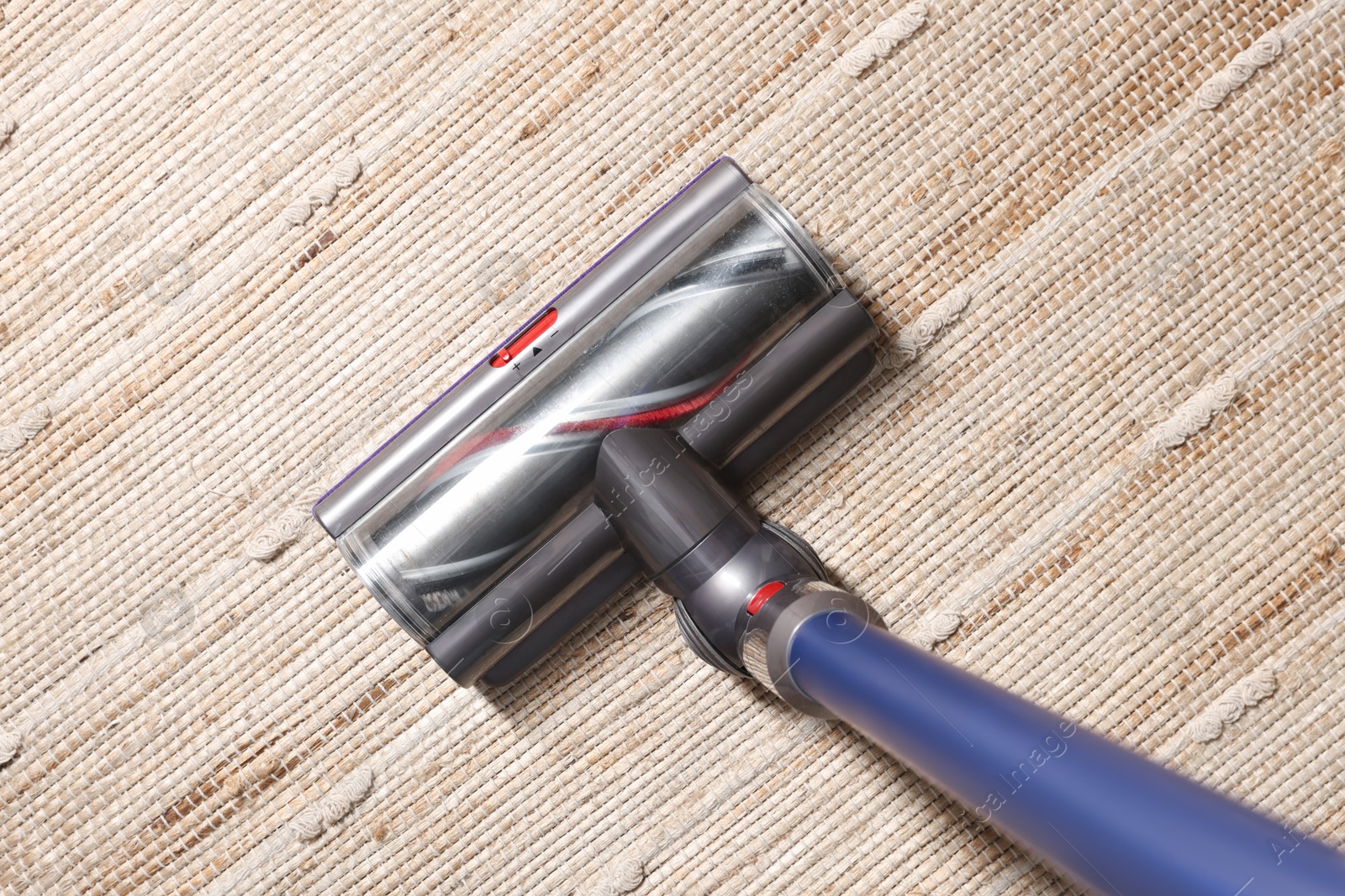 Photo of Cleaning carpet with cordless vacuum cleaner indoors, top view