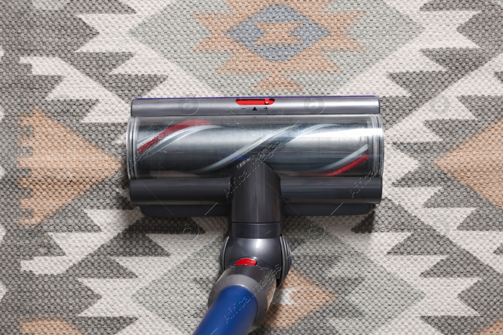 Photo of Cleaning carpet with cordless vacuum cleaner indoors, top view