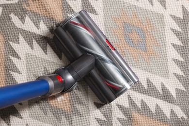 Photo of Cleaning carpet with cordless vacuum cleaner indoors, top view