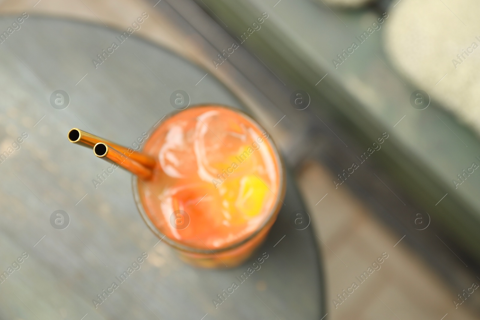 Photo of Glass of tasty refreshing drink and straws on table, top view