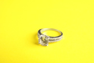 Photo of Beautiful bijouterie. Elegant ring on yellow background, closeup