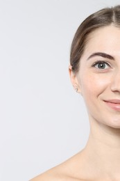 Photo of Beautiful young woman after henna eyebrows dyeing on light background, closeup