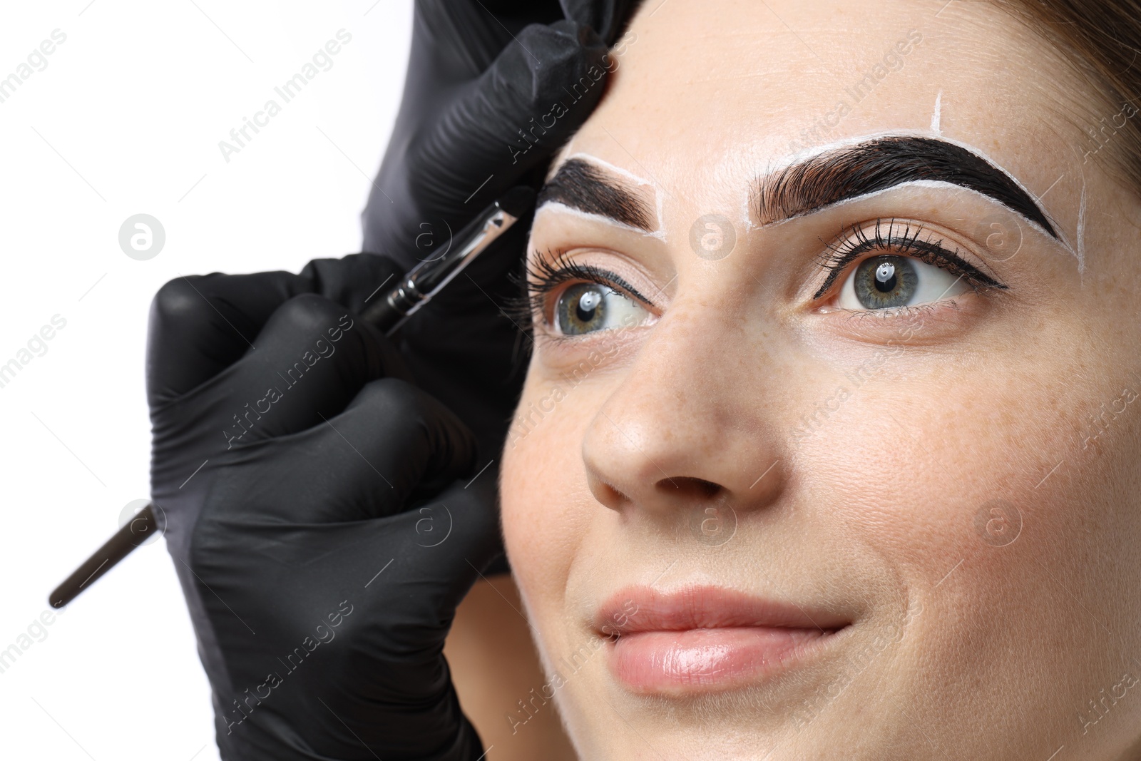 Photo of Young woman undergoing henna eyebrows dyeing procedure on light background, closeup