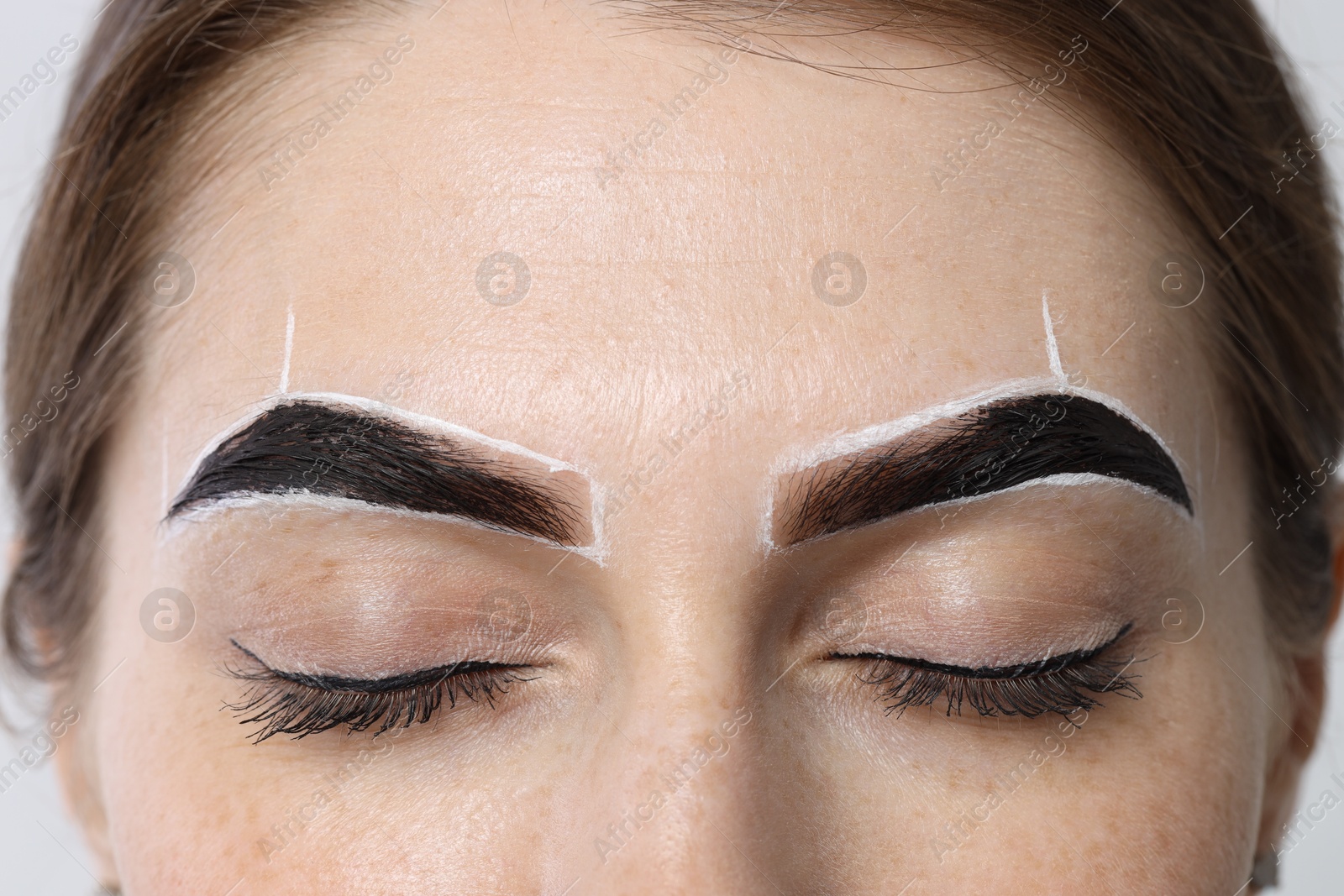 Photo of Young woman during henna eyebrows dyeing procedure, closeup