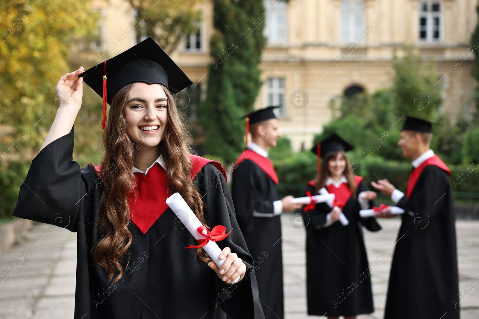 Photo of Happy students with diplomas after graduation ceremony outdoors, selective focus