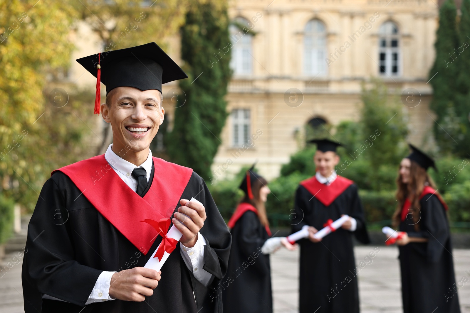 Photo of Happy students with diplomas after graduation ceremony outdoors, selective focus