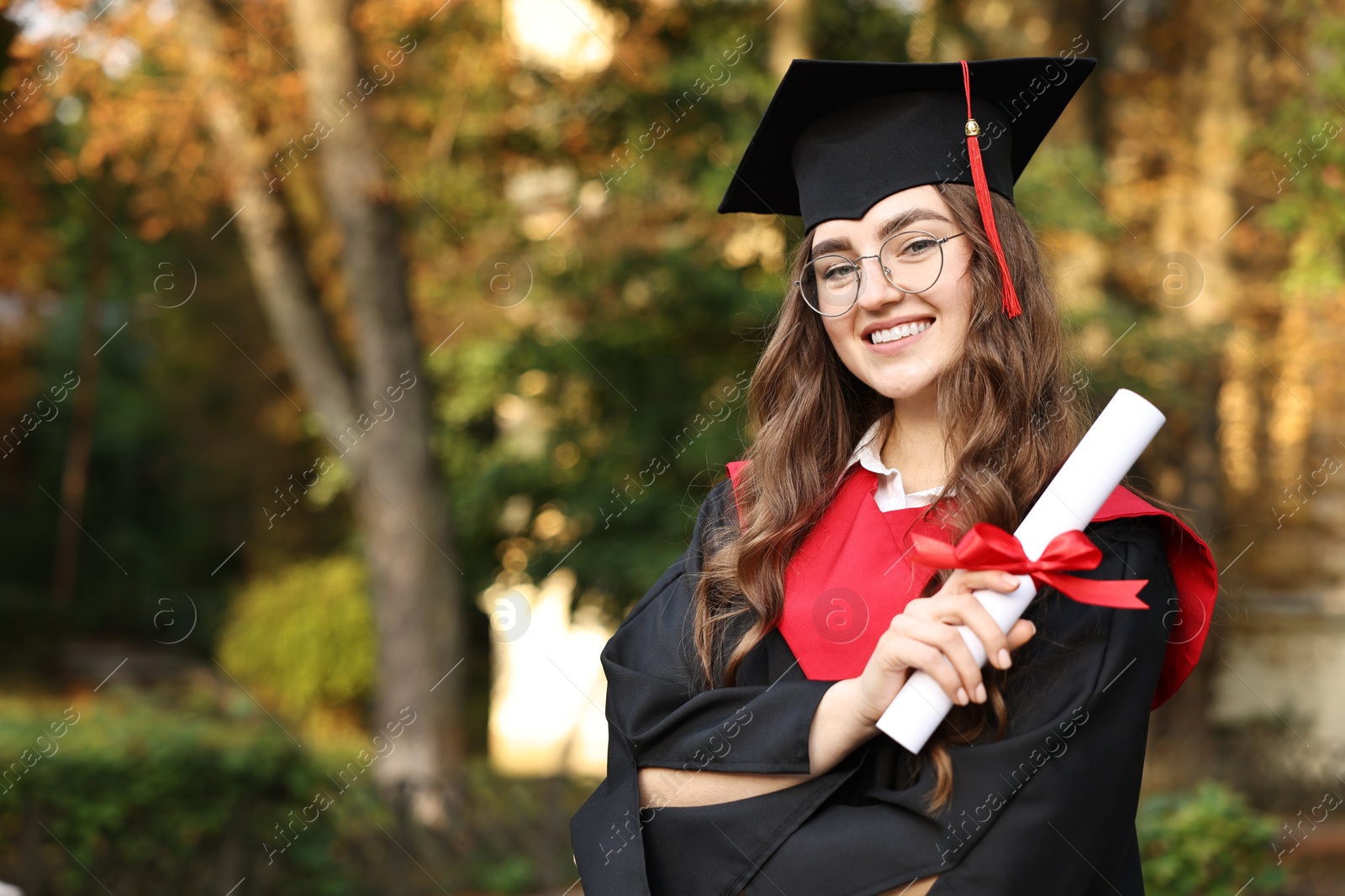 Photo of Happy student with diploma after graduation ceremony outdoors, space for text