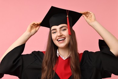 Photo of Happy student after graduation on pink background