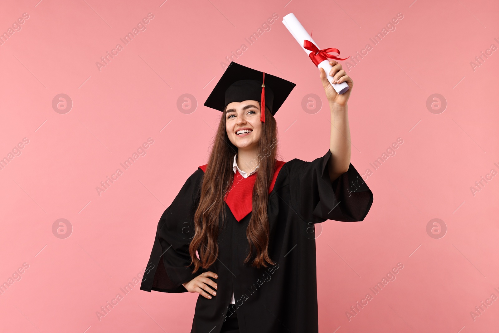 Photo of Happy student with diploma after graduation on pink background