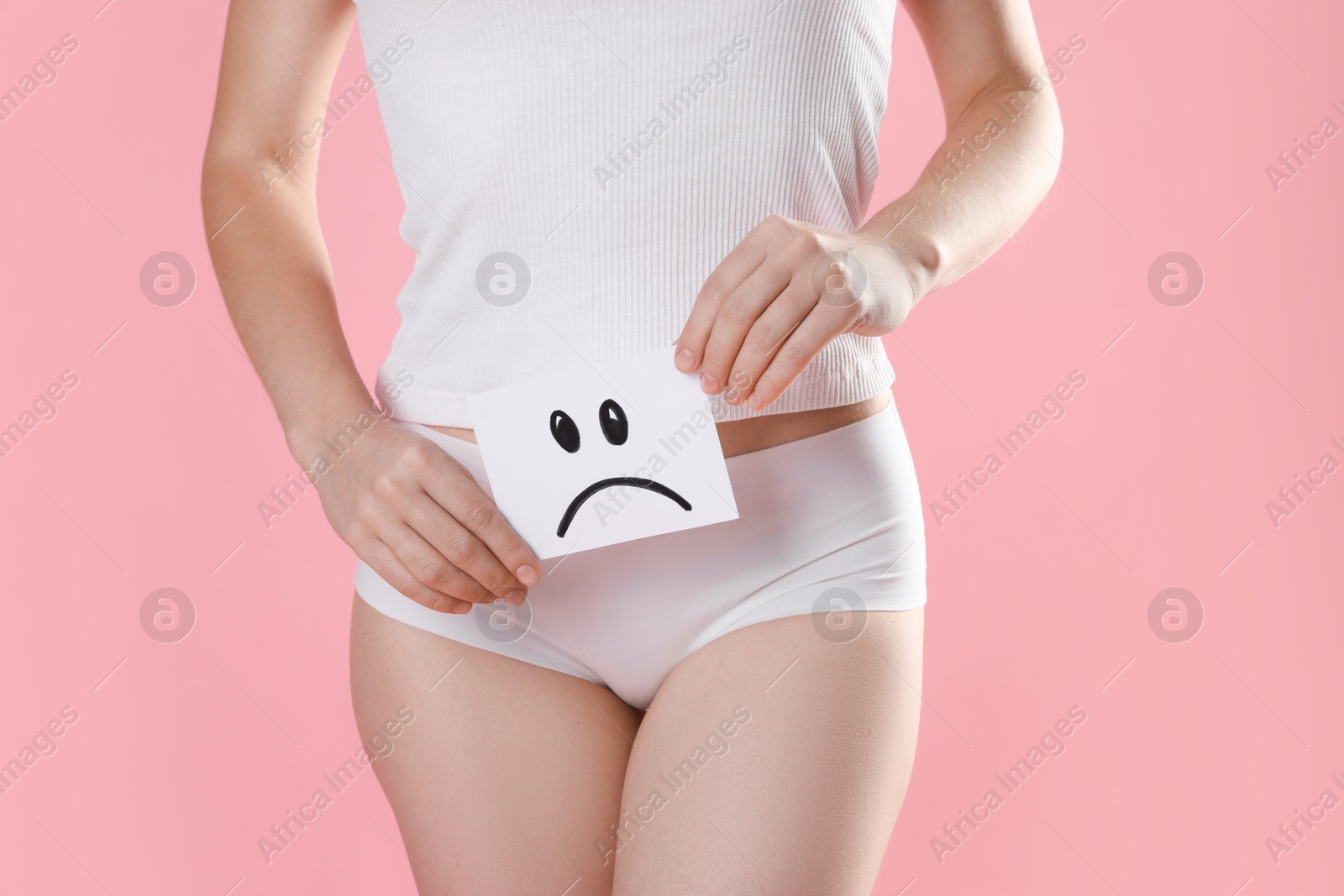 Photo of STD (sexually transmitted disease). Woman holding sticky note with drawn sad face on pink background, closeup