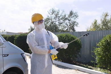 Photo of Pest control worker with spray tank outdoors