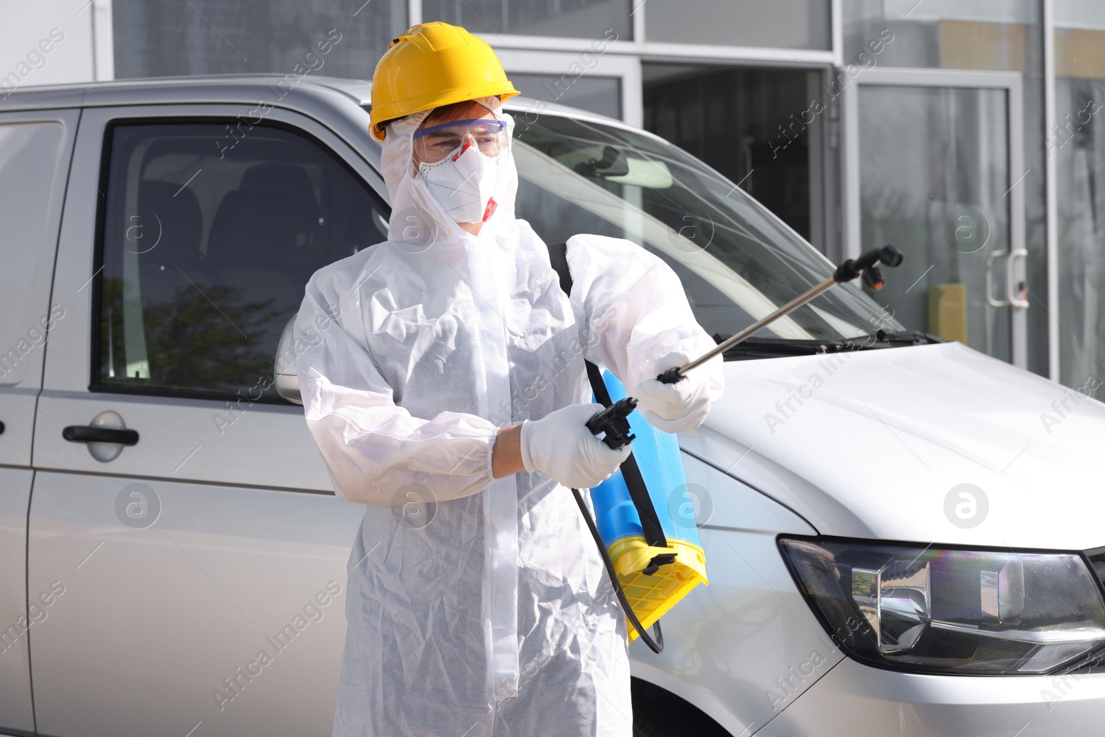 Photo of Pest control worker with spray tank near gray minibus outdoors