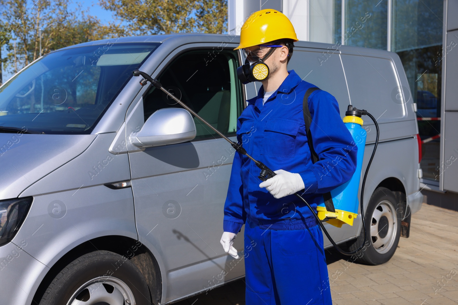 Photo of Pest control worker with spray tank near gray minibus outdoors