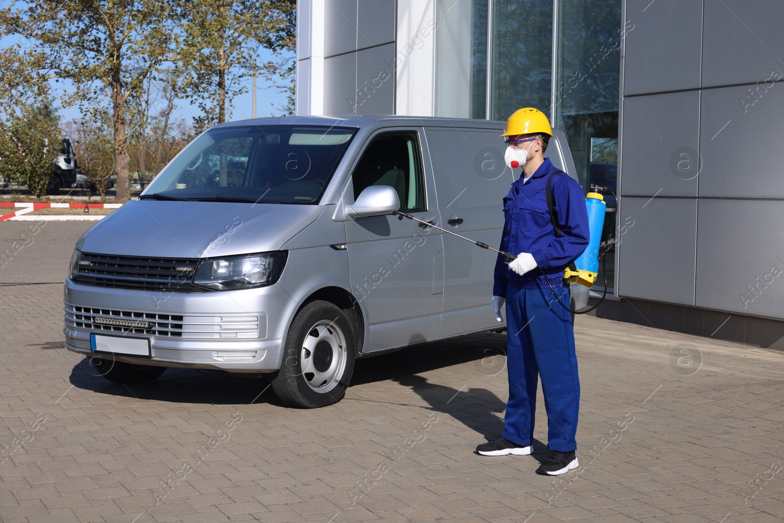 Photo of Pest control worker with spray tank outdoors