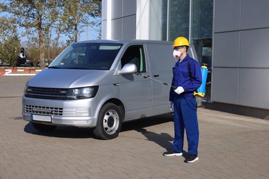 Photo of Pest control worker with spray tank outdoors