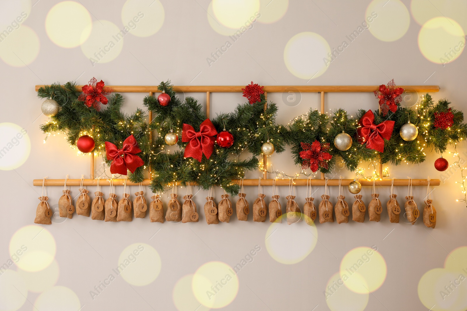 Photo of Christmas advent calendar with gifts and decor hanging on white wall indoors