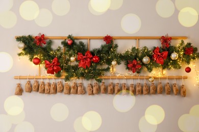 Photo of Christmas advent calendar with gifts and decor hanging on white wall indoors