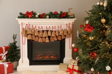 Photo of Advent calendar with gifts and decor hanging on fireplace Christmas near tree indoors