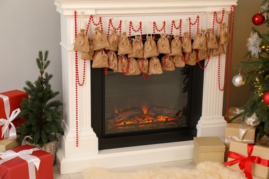 Photo of Advent calendar with gifts and decor hanging on fireplace Christmas near tree indoors