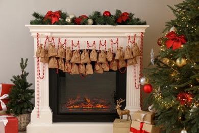 Photo of Advent calendar with gifts and decor hanging on fireplace Christmas near tree indoors