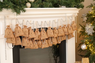 Photo of Advent calendar with gifts and decor hanging on fireplace Christmas near tree indoors