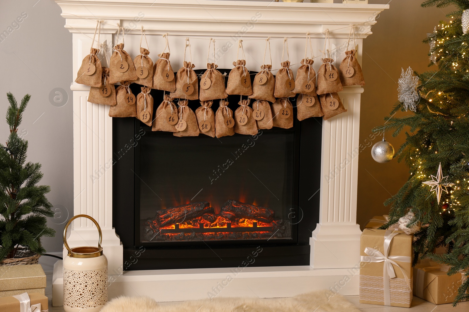 Photo of Advent calendar with gifts and decor hanging on fireplace Christmas near tree indoors