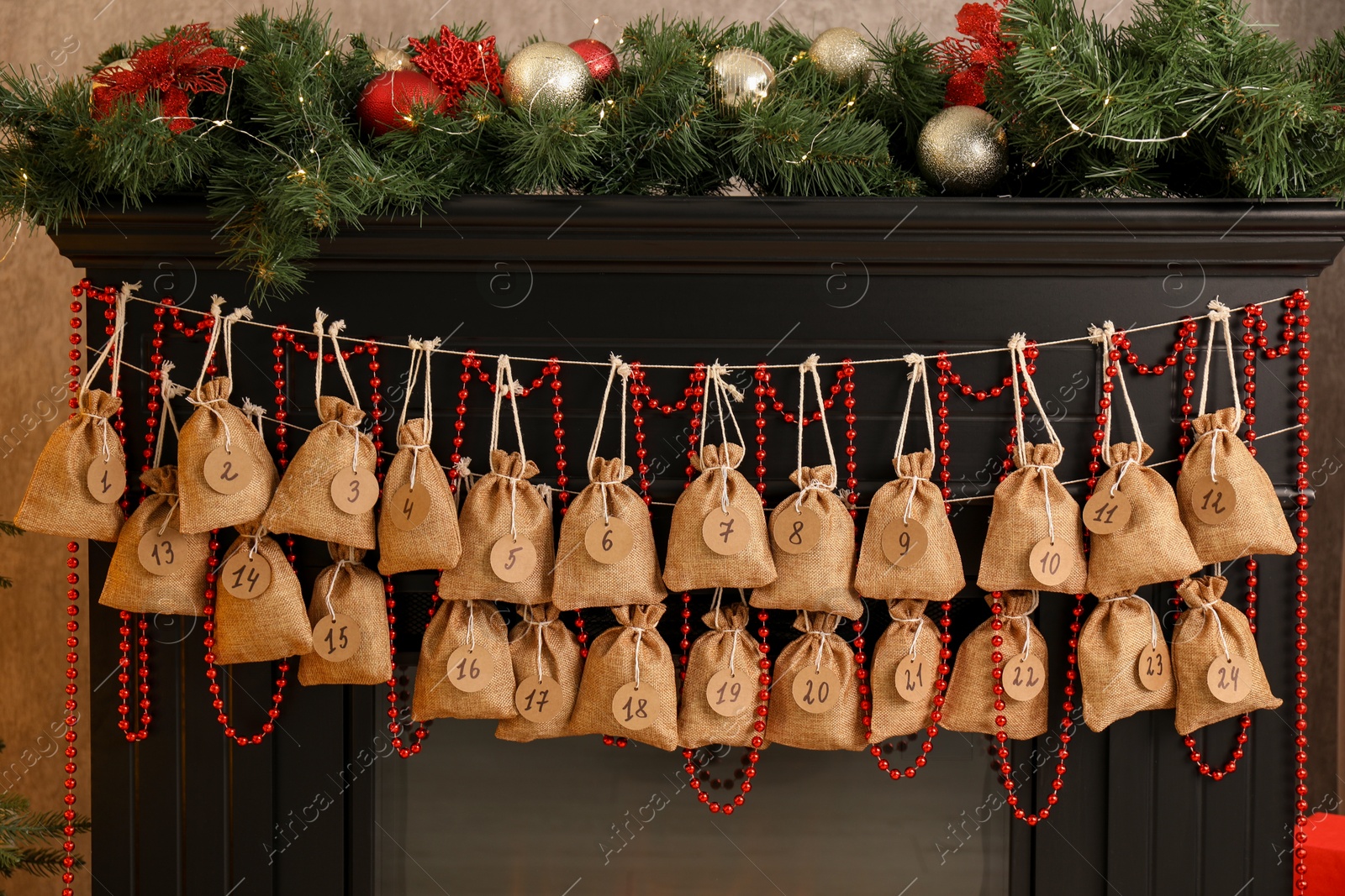 Photo of Christmas advent calendar with gifts and decor hanging on fireplace indoors