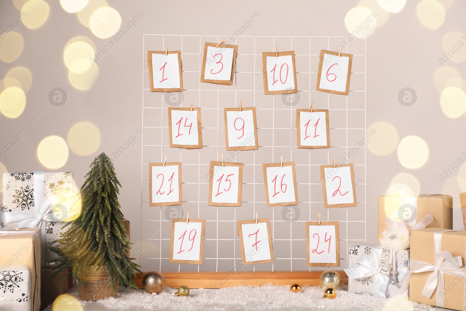 Photo of Handmade advent calendar, gifts and decor on table near light wall. Christmas tradition