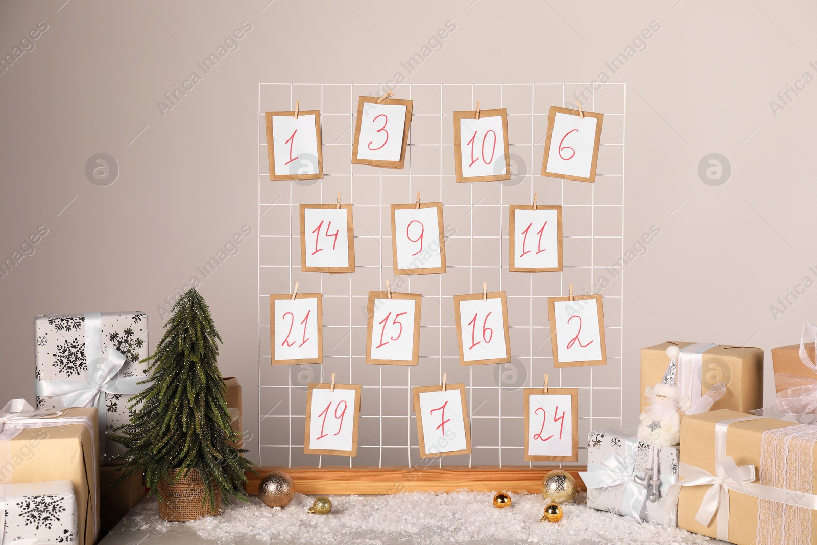 Photo of Handmade advent calendar, gifts and decor on table near light wall. Christmas tradition