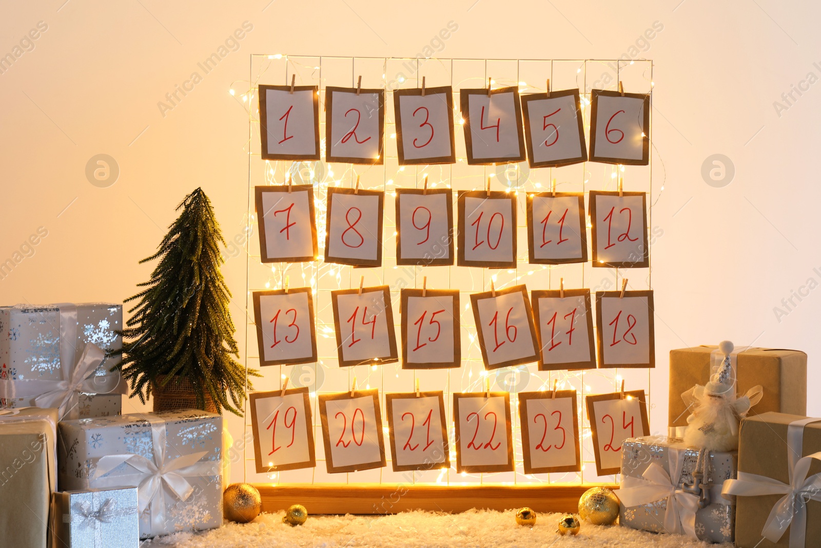 Photo of Handmade advent calendar, gifts and decor on table near light wall. Christmas tradition