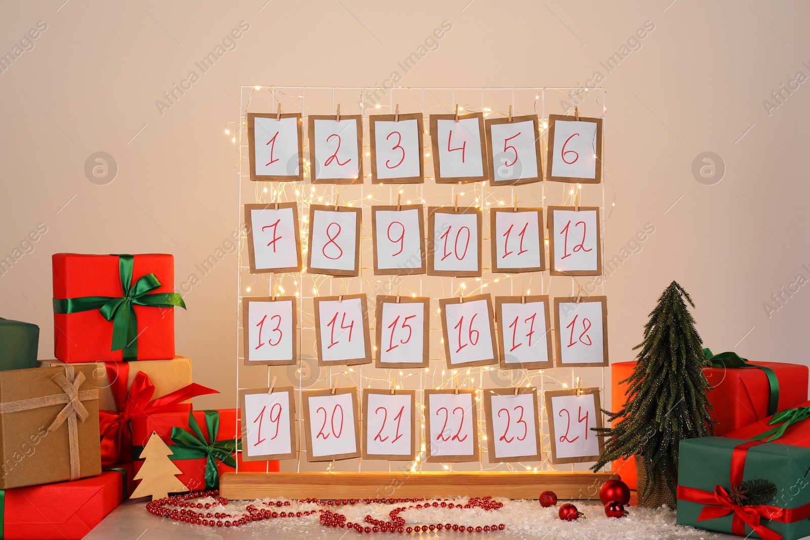 Photo of Handmade advent calendar, gifts and decor on table near light wall. Christmas tradition