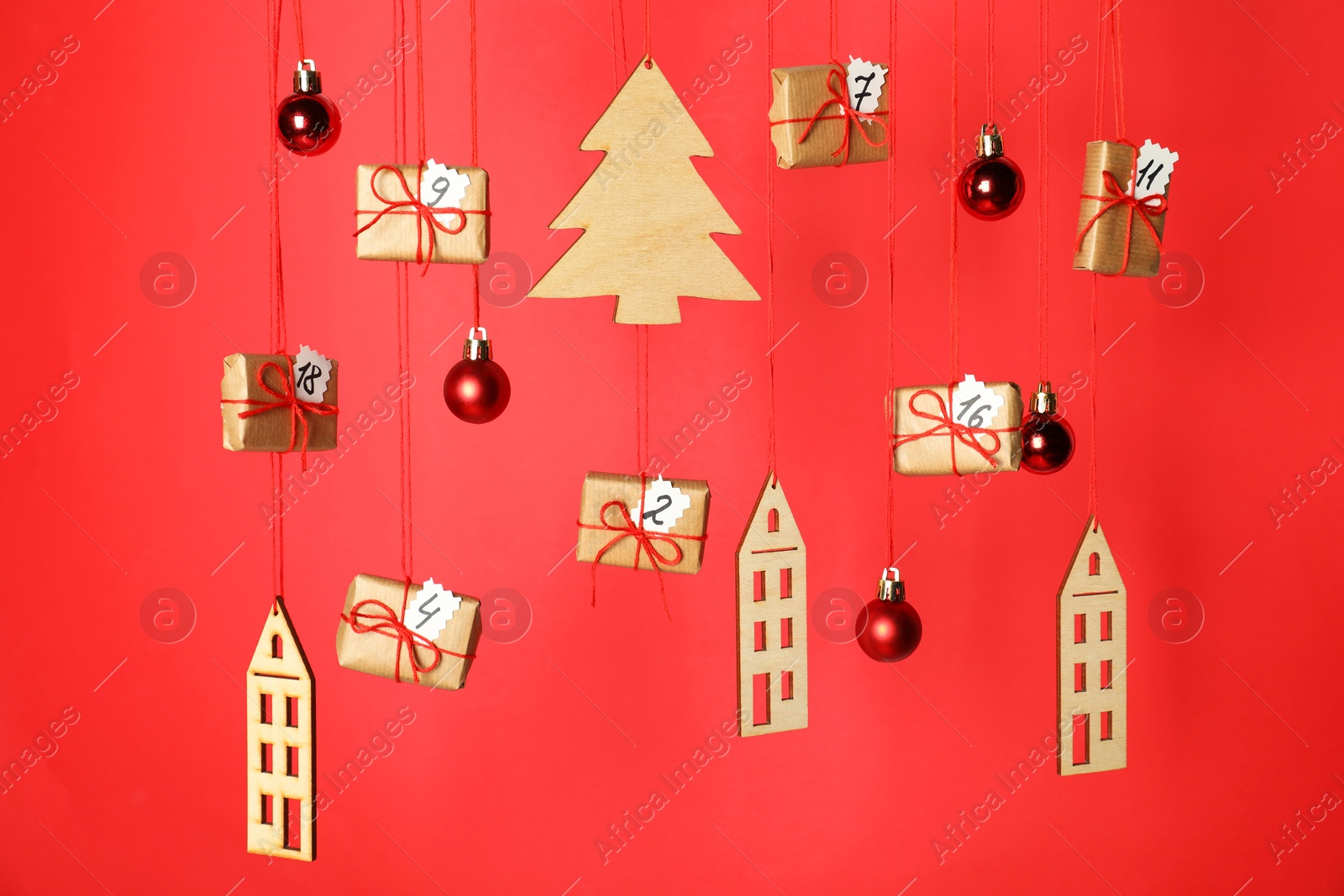 Photo of Handmade advent calendar with decor hanging on red background. Christmas tradition