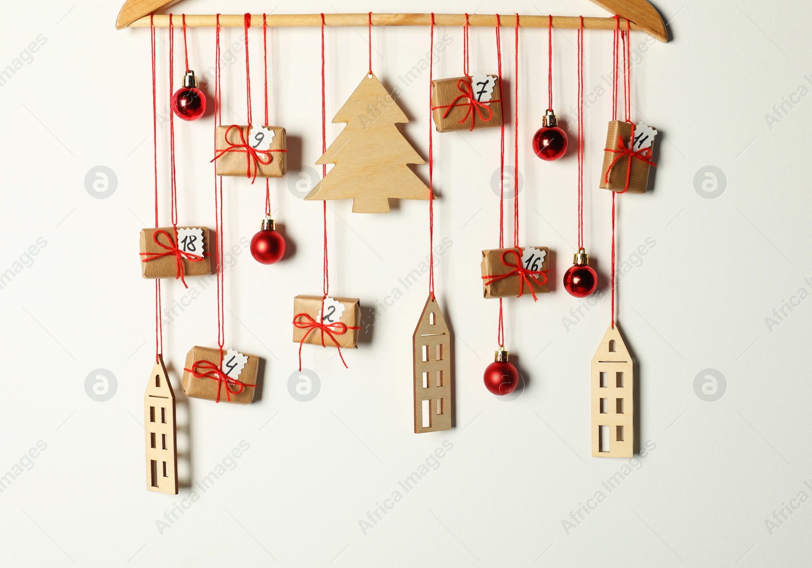 Photo of Handmade advent calendar with decor hanging on white background. Christmas tradition