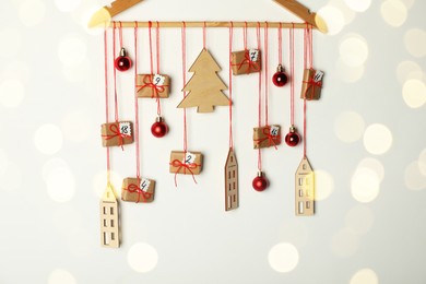 Photo of Handmade advent calendar with decor on hanger against white background. Christmas tradition