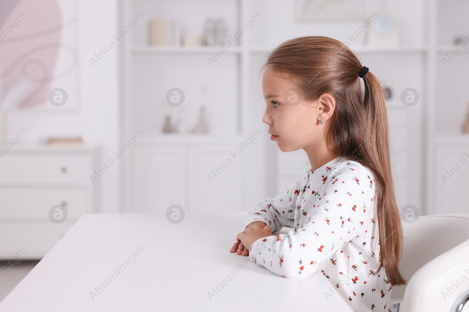 Photo of Girl with correct posture sitting at white desk indoors