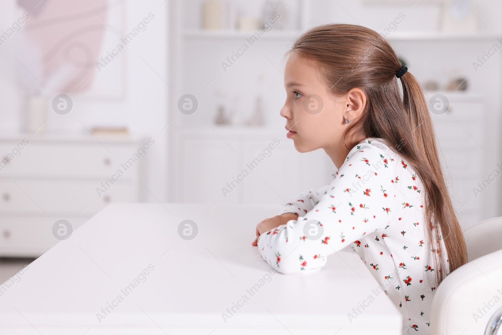 Photo of Girl with incorrect posture sitting at white desk indoors