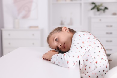 Photo of Girl with incorrect posture sitting at white desk indoors