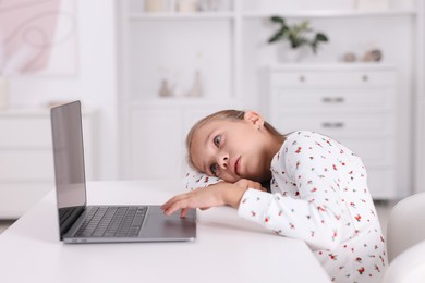 Girl with incorrect posture using laptop at white desk indoors