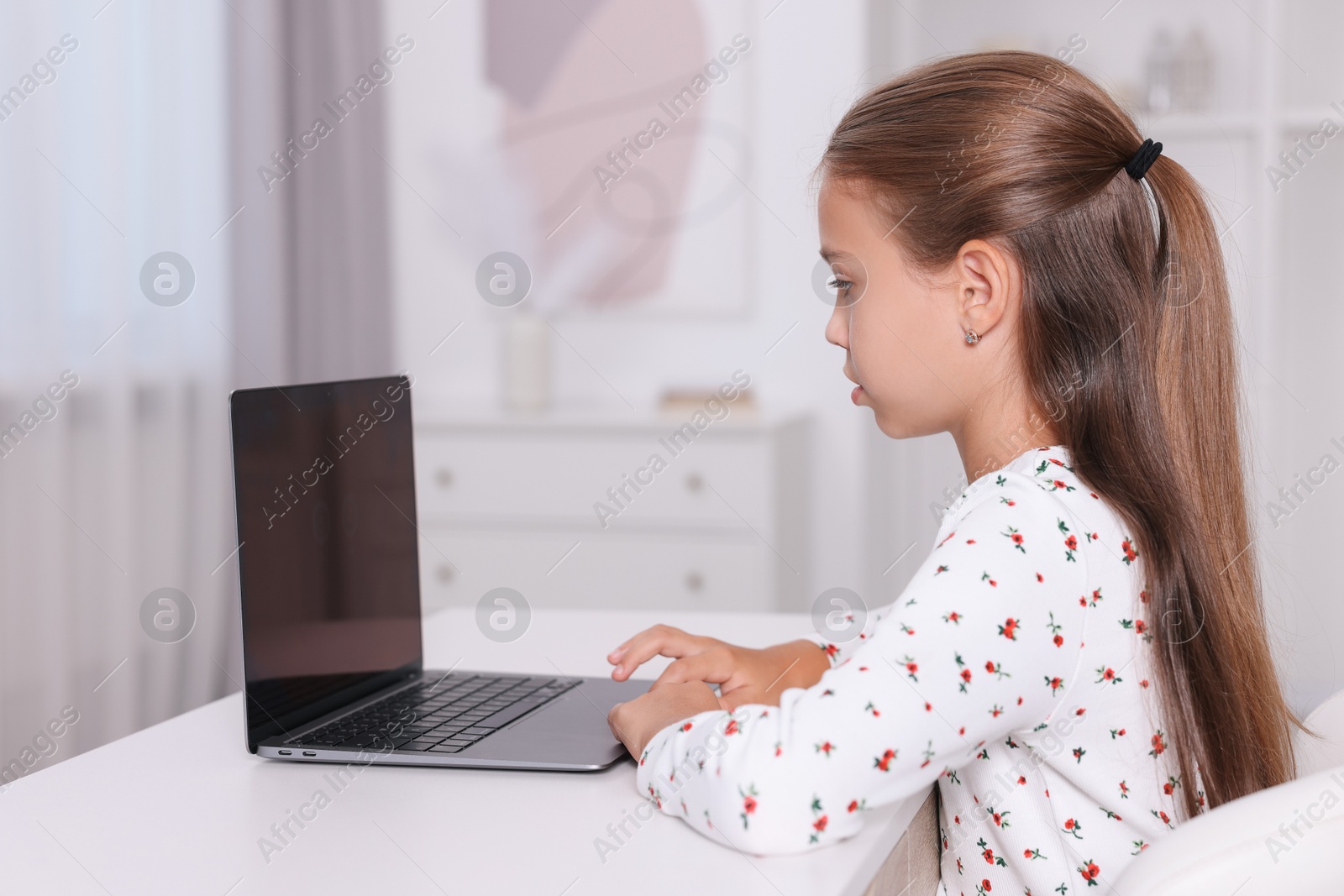 Photo of Girl with correct posture using laptop at white desk indoors