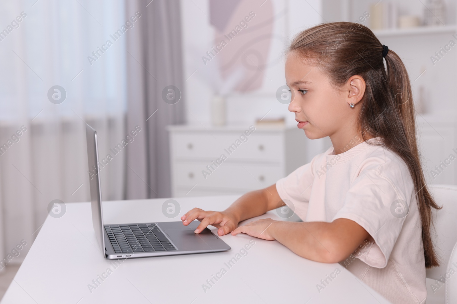 Photo of Girl with correct posture using laptop at white desk indoors