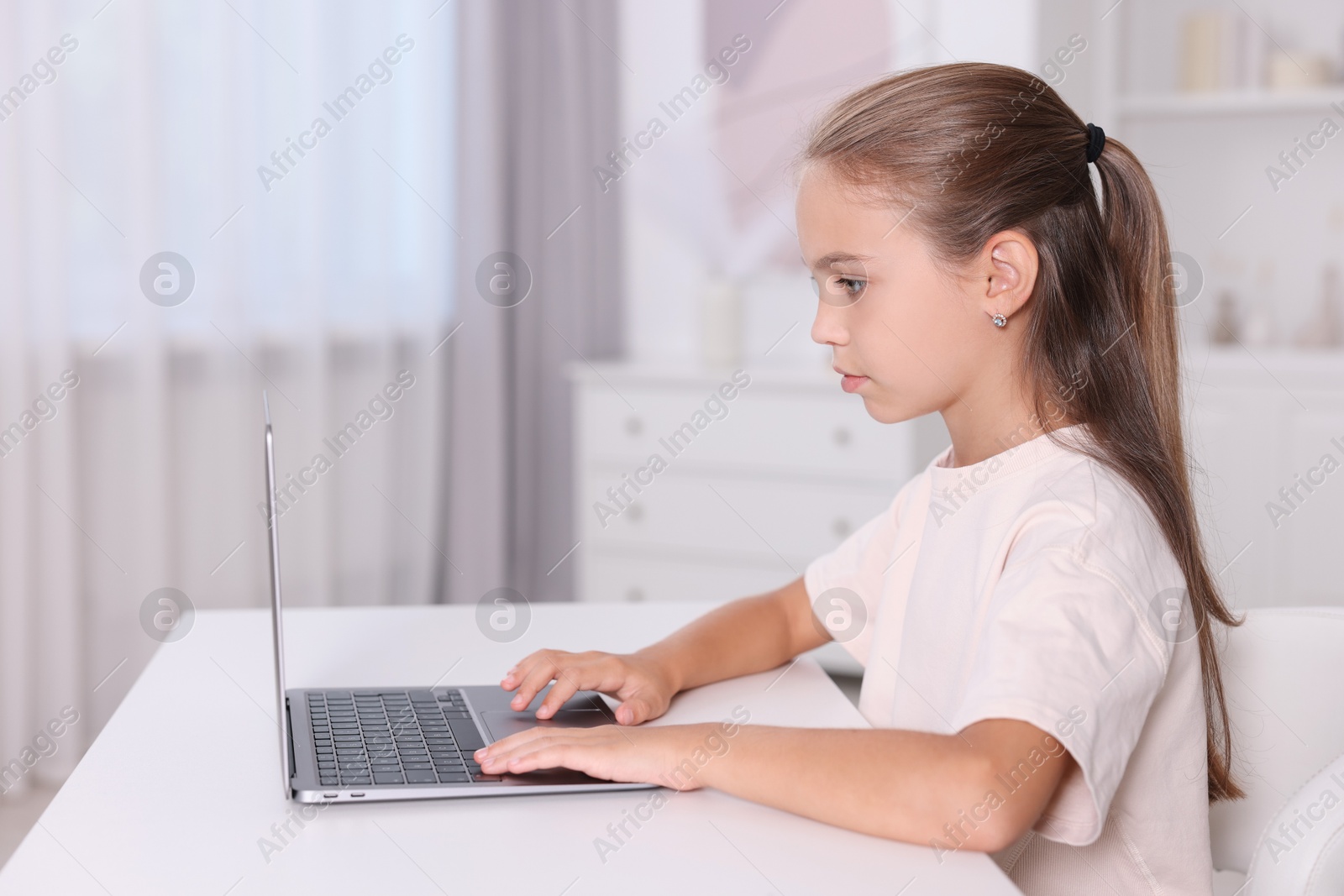 Photo of Girl with correct posture using laptop at white desk indoors