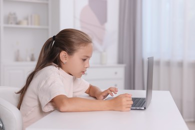 Photo of Girl with incorrect posture using laptop at white desk indoors