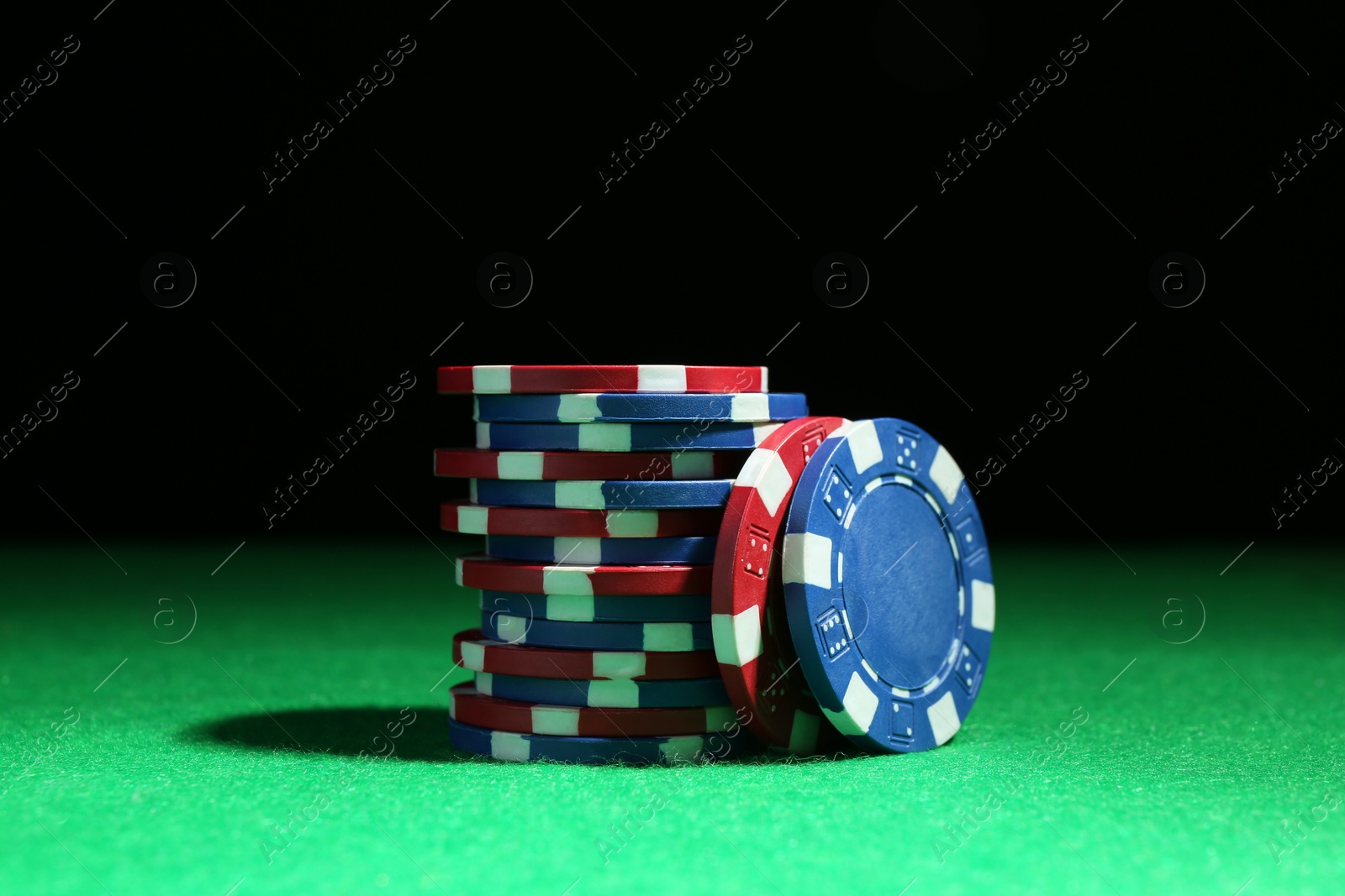 Photo of Poker chips on green table against dark background, closeup