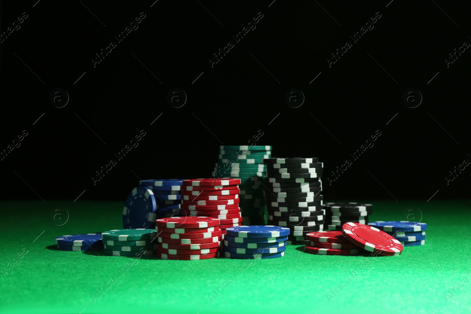 Photo of Poker chips on green table against dark background